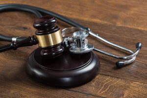 A wooden gavel and a black and silver metal stethoscope sit atop a wooden table