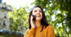 A woman smiles while talking on her cell phone outdoors