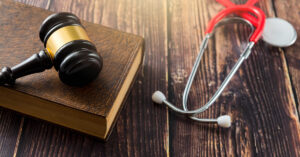 A gavel sitting on a book next to a stethoscope