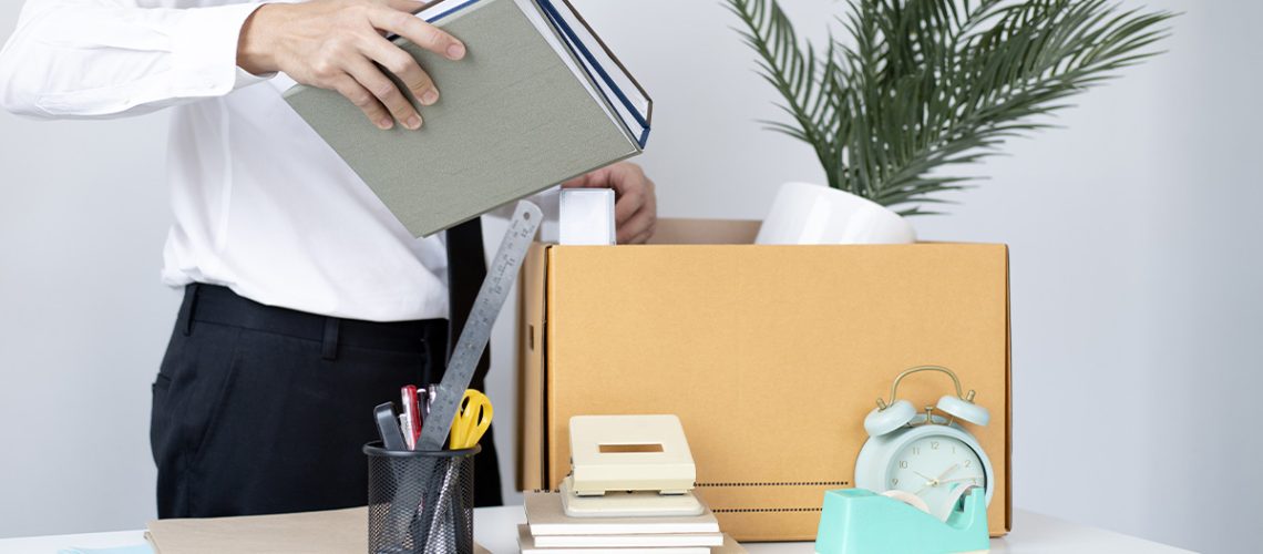 A businessman packing up his office items in a cardboard box