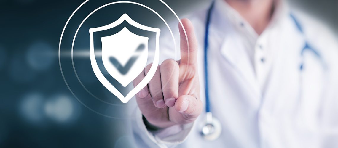 A doctor with a blue stethoscope hanging behind his neck holds up his index finger pointed at a shield with a check mark imprinted in it