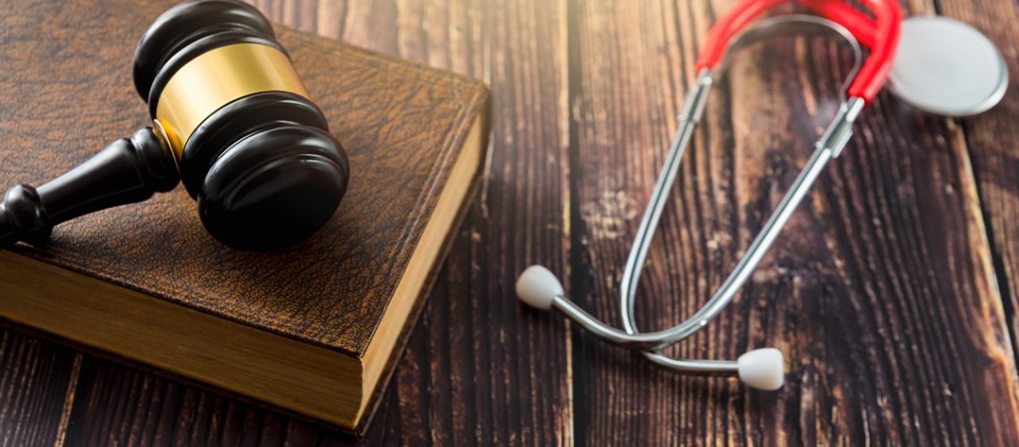 A gavel sitting on a book next to a stethoscope