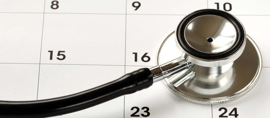 A silver and black stethoscope laying face down on a black and white calendar